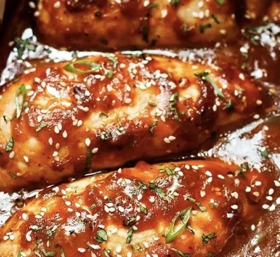 Freshly baked chicken breasts served with vegetables on a plate.