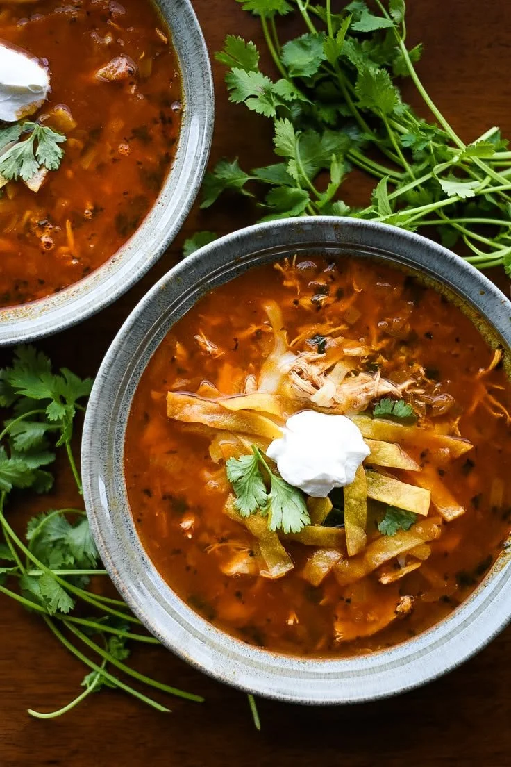 Bowl of authentic Chicken Tortilla Soup garnished with tortilla strips and cilantro
