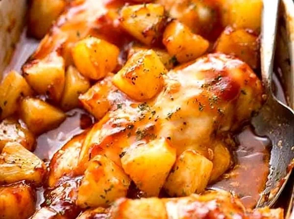 Baked pineapple barbecue chicken dish garnished with fresh herbs on a plate