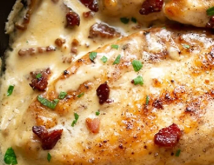 Creamy bacon chicken dish garnished with herbs on a plate