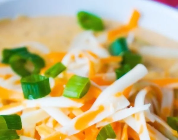 Bowl of creamy ground chicken chili topped with fresh herbs and cheese