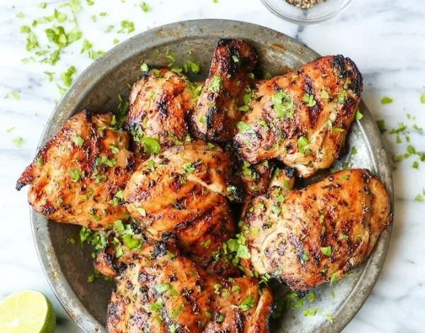 Plate of flavorful Thai chicken thighs garnished with herbs and spices.