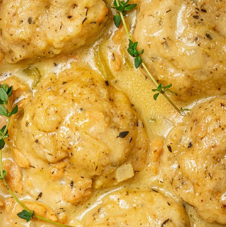 Bowl of vegan chicken and dumplings with fresh herbs